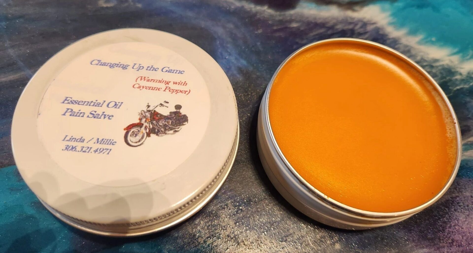 A tin of orange wax sitting next to another tin.